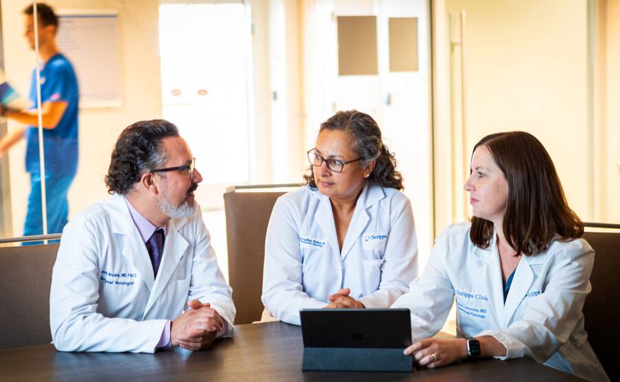 Three Scripps Cancer Center oncologists review incoming physician referrals for cancer patients on a tablet.