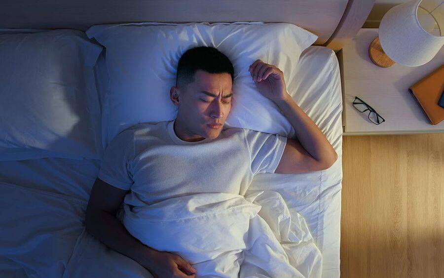An Asian man appears to have discomfort while sleeping, which represents an aspect of chest pain per a Scripps cardiologist.