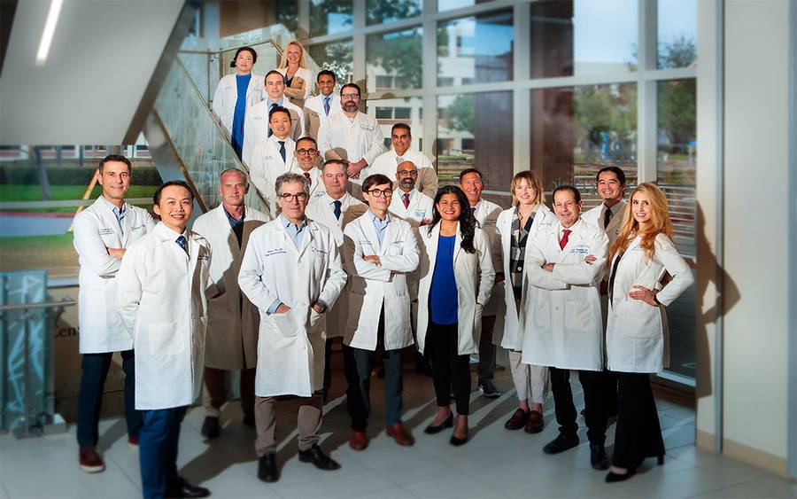 A group of Scripps Clinic cardiologists in a group picture on the stairs in a brightly lit atrium.