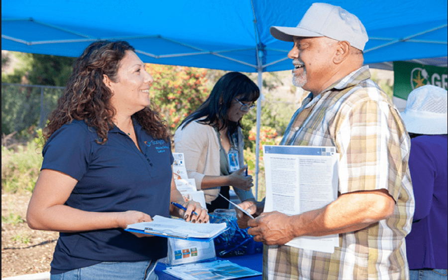 A mature woman shares diabetes care information with a mature man, representing bilingual diabetes care and prevention.