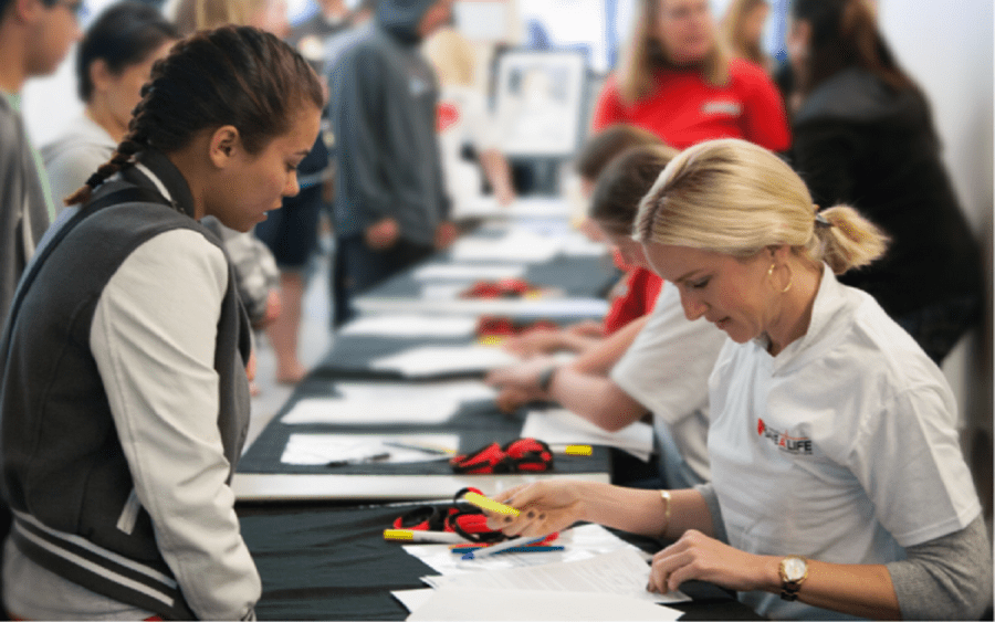 A woman reviews  paperwork with a young athlete, representing the sudden cardiac arrest screening program through Scripps. 