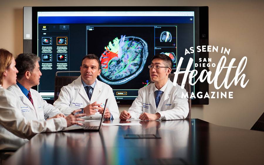 Scripps neuro-oncology team members sit at a table as they collaborate on treatment options.