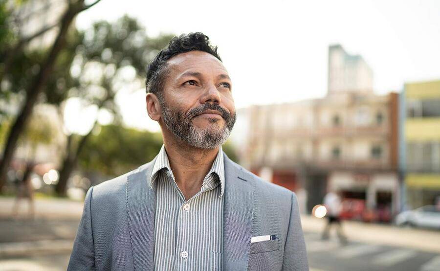 A mature multi-ethnic man stands near a busy street, representing head and neck cancer treatment at Scripps Cancer Center.
