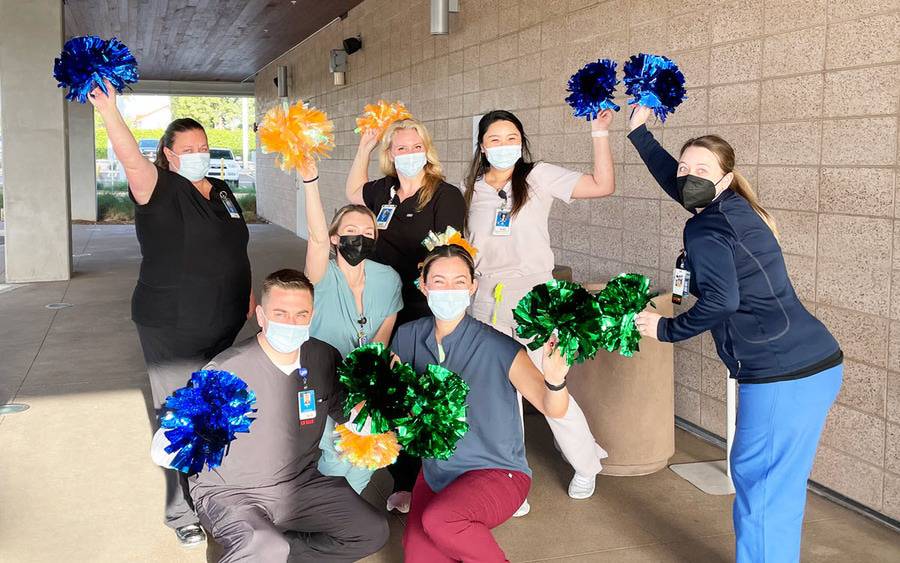 Scripps Health employees celebrate with orange and blue pom-poms.