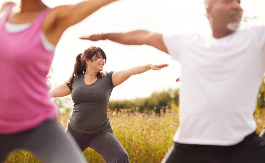 A group of people practice yoga to help prevent heart disease.