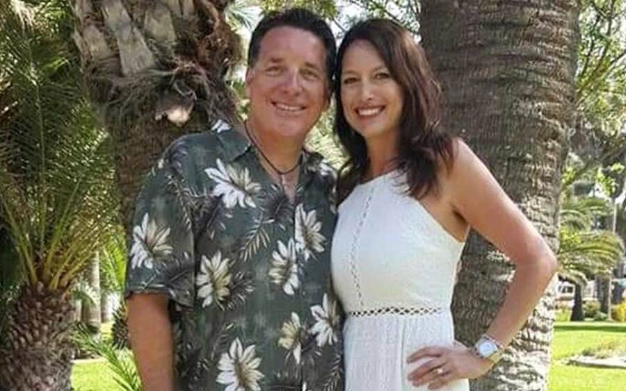 Bobby Day poses with his wife Michele outdoors by palm trees.