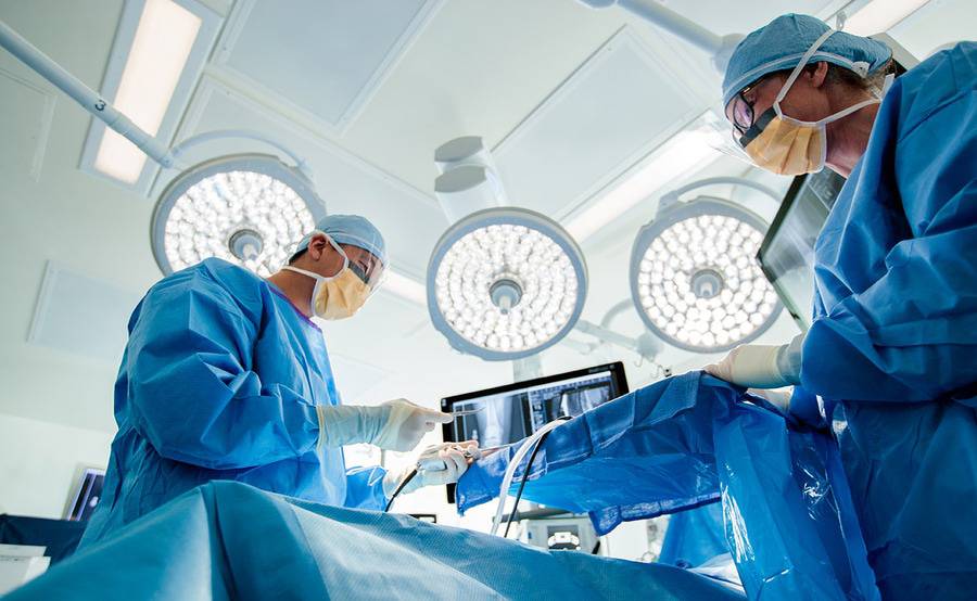 Two doctors in blue surgical gowns operate on a patient in a surgery setting, representing quality at Scripps Health.