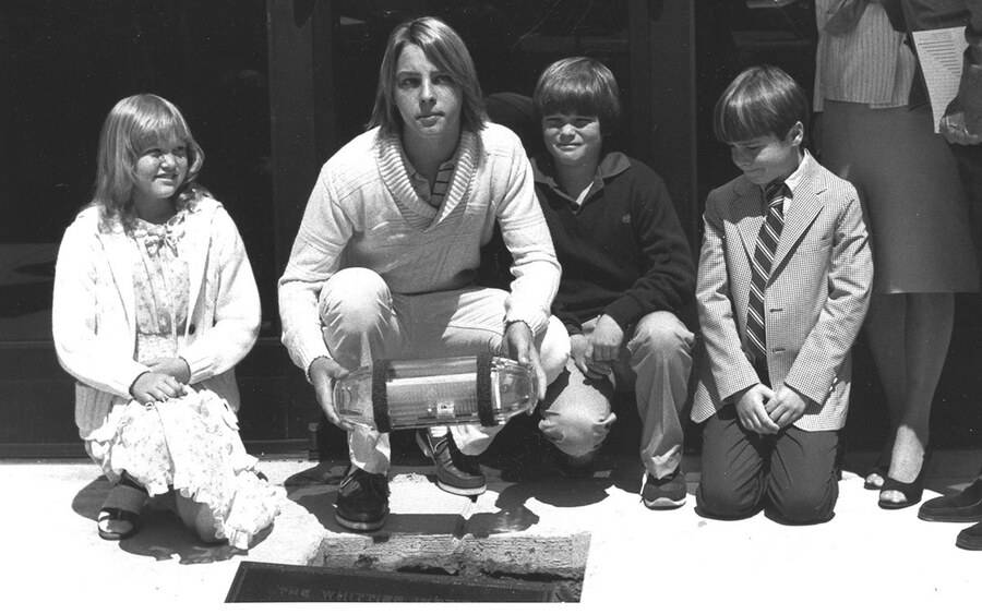 Four children lower a time capsule into the ground.