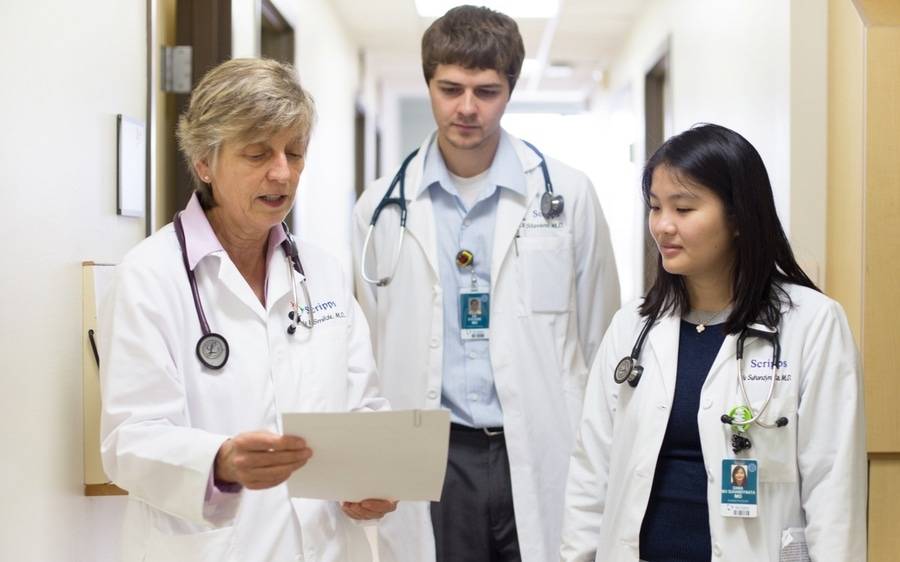 Scripps doctors review a medical report as they walk through the halls of a Scripps building.