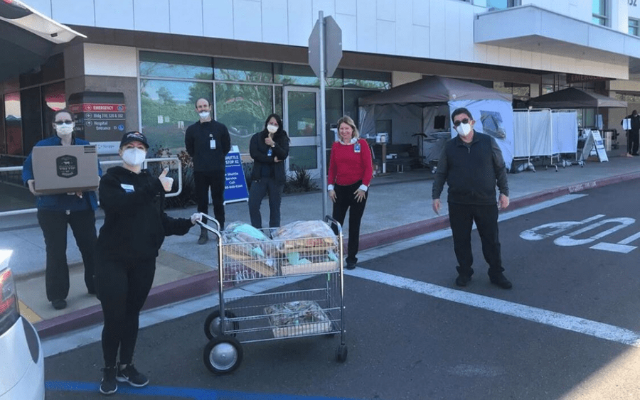 Grateful Scripps workers receiving medical supply donations in front of hospital.