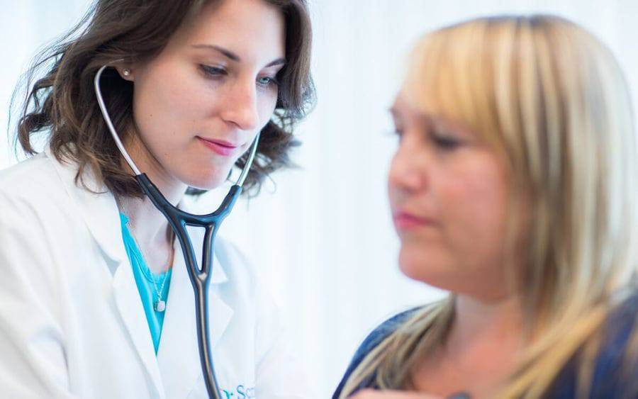 A Scripps doctor takes vitals on a patient with her stethoscope at a Scripps walk-in clinic.