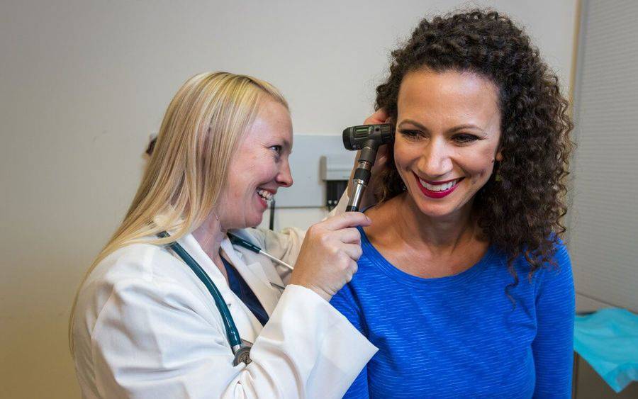 A Scripps HealthExpress walk-in clinic provider smiles while talking to patient in lab room