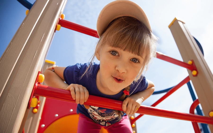 Child smiles as he goes down slide in a safe playground. 