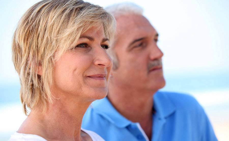 A smiling middle-aged couple on the beach represent the full life that can be led after skin cancer treatment.