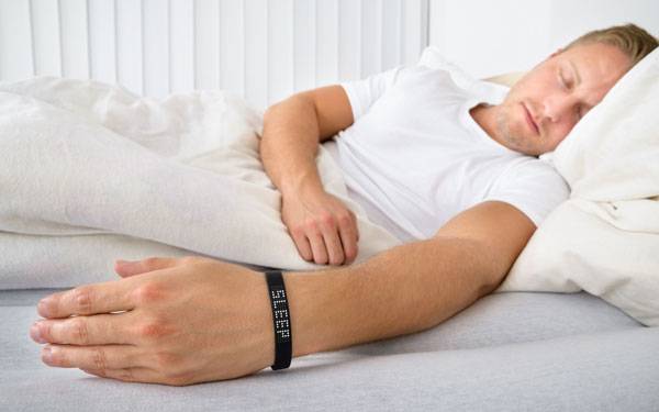 A man asleep with a sleep tracker on his wrist.