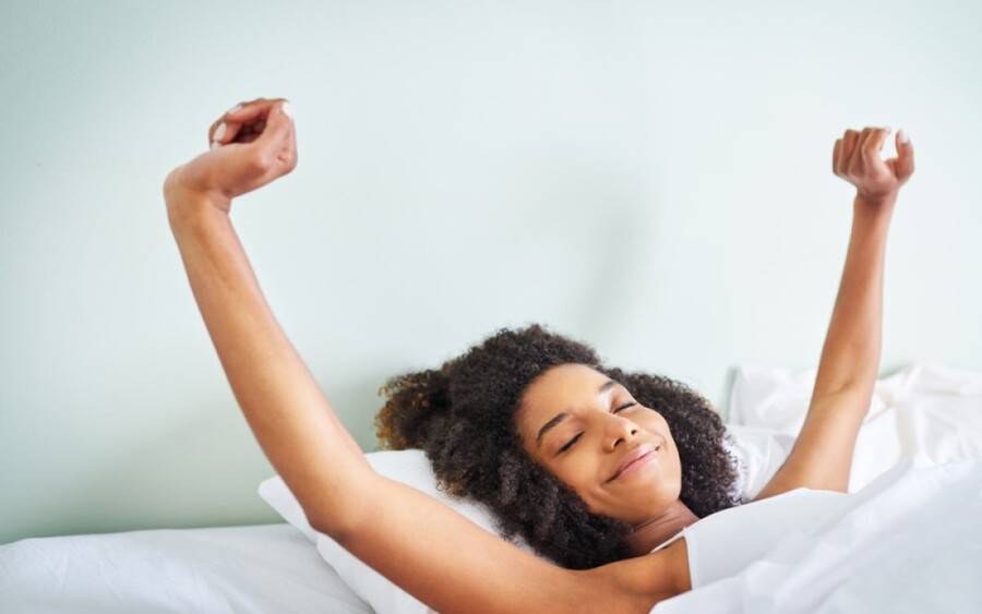 An African-American woman wakes up after a good night of sleep.