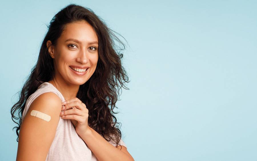 Woman smiles after getting flu and COVID vaccines