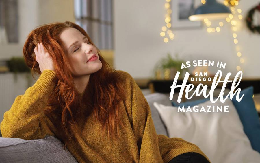 Woman sitting on her couch having a quiet moment to herself, illustrating taking a mindful moment during the holiday season.