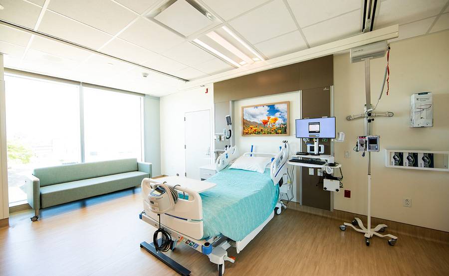 Nurses, a mother and her newborn being transported to their postpartum room down a hospital hallway.