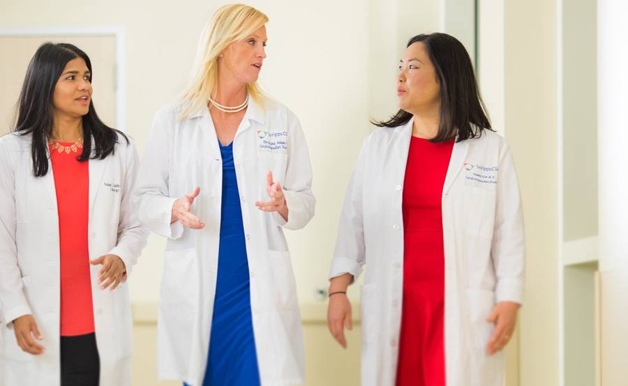 Three female cardiologists talking in a hospital hallway represent the expertise in women's heart care at Scripps.