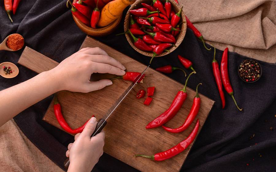 A cook cuts chili peppers, which can help lower blood pressure.