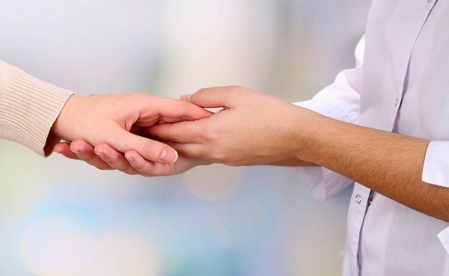 One hand holds and supports another hand, representing spiritual and emotional support provided at Scripps Health in San Diego.