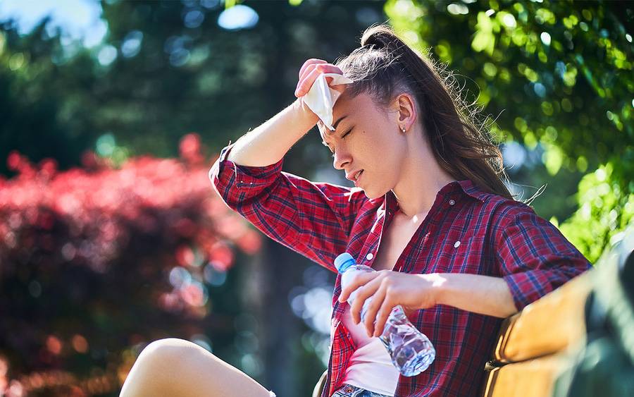 A woman with a headache due to hot summer weather tries to stay cool with water.