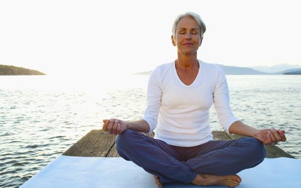   A woman meditates on a dock, similar to the practices taught during the mindfulness-based stress reduction course at Scripps Center for Integrative Medicine in San Diego