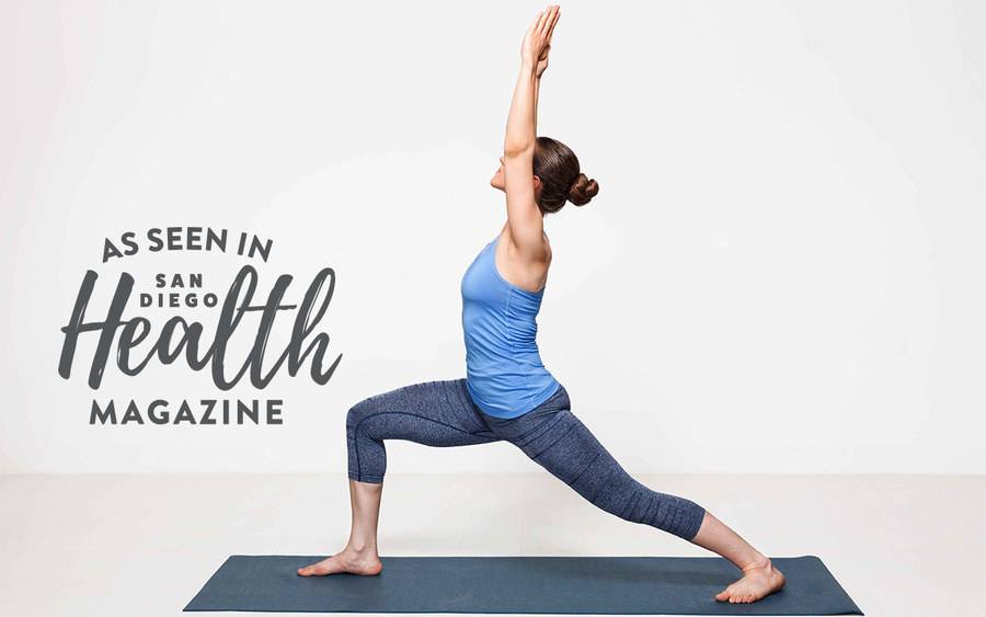 A woman on a yoga mat raises her arm into the air, representing the mind, body and spirit benefits of practicing yoga.