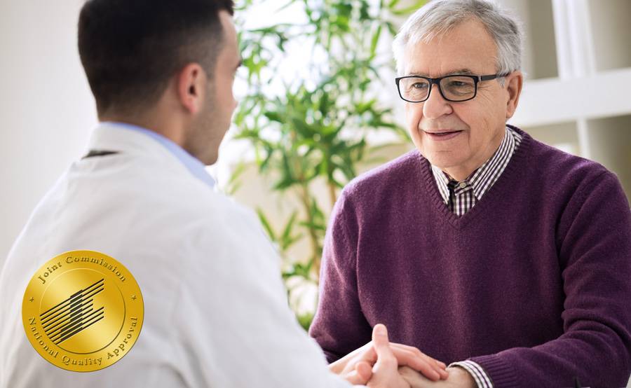 A smiling mature man talks with his doctor while holding hands, representing the expert stroke care at Scripps.