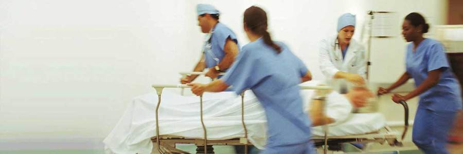 Doctors and Nurses going down hallway with patient in bed