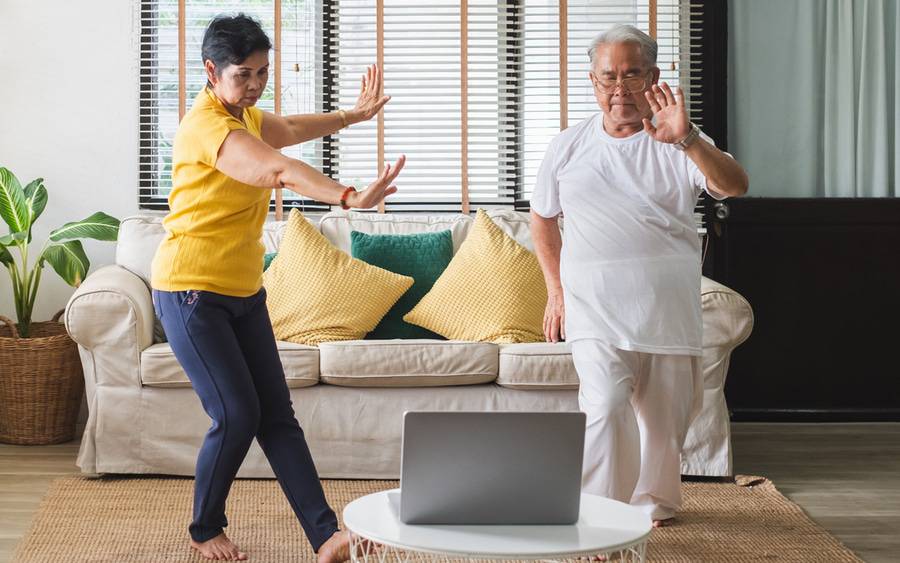 An older couple learning Tai Chi in their own home to improve balance and decrease stress.