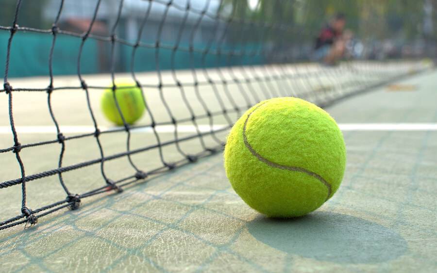 Two tennis balls near a net on a tennis court representing an ovarian cancer diagnosis by tennis legend, Chris Evert.