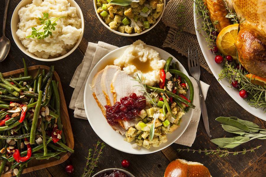 A table is setup with a traditional Thanksgiving meal including turkey, stuffing, mashed potatoes and green beans.
