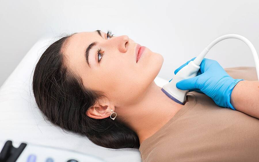 A woman has her neck checked for signs of thyroid disease.