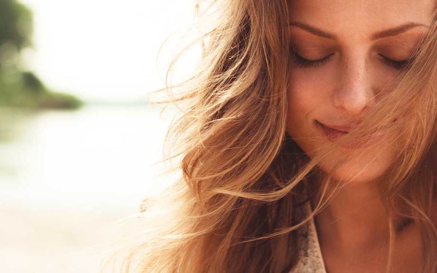 A smiling woman protects her skin by visiting the beach in the early evening.