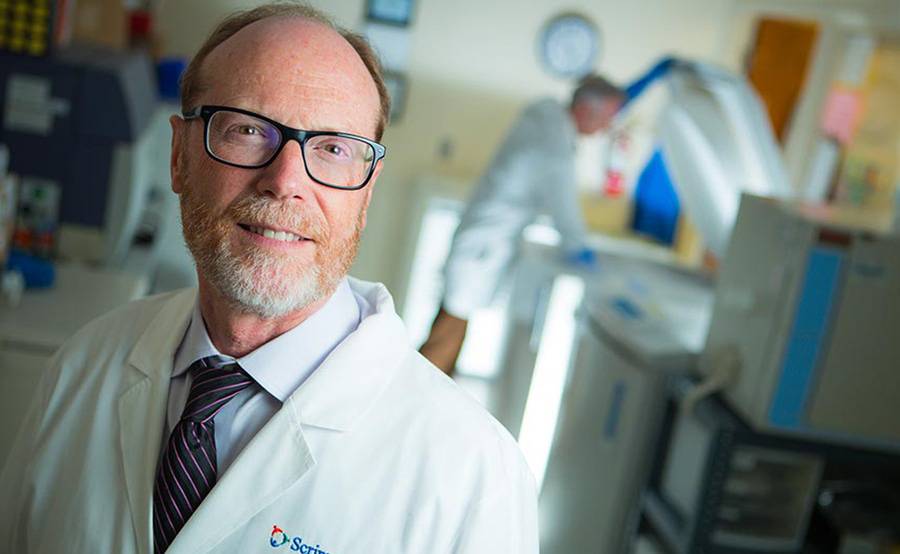 A mature male transplant blood and marrow transplant surgeon at Scripps Health stands proud in a clinical lab setting.