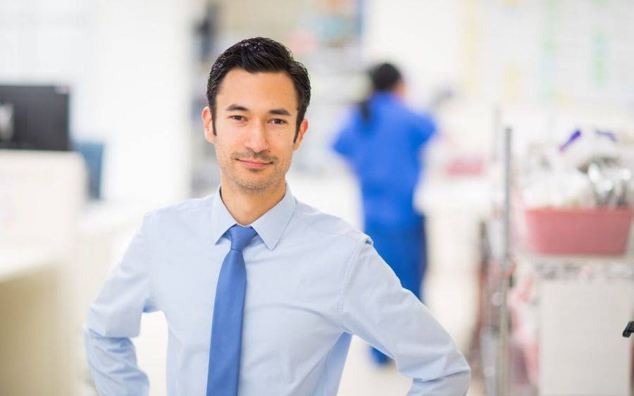 Troy Drysdale, a Scripps pharmacist, stands in the foreground of a hospital setting as part of a feature on the UCSF website.