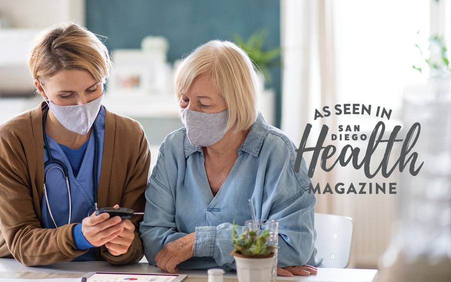 A home health provider and a patient looking at a glucose meter for monitoring diabetes.