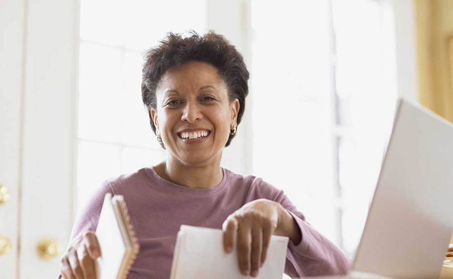 A smiling middle-aged African-American woman represents the full life that can be led after uterine sarcoma treatment.