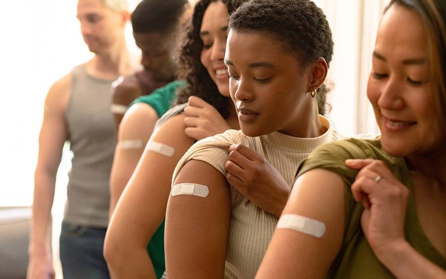 Group of young adults showing bandages over their shoulders where they received vaccinations.