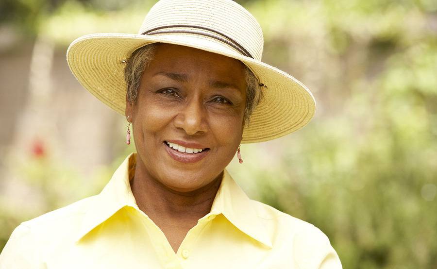 A smiling middle-aged woman in a sun hat represents a fuller life with treatment or surgery for vascular disease.