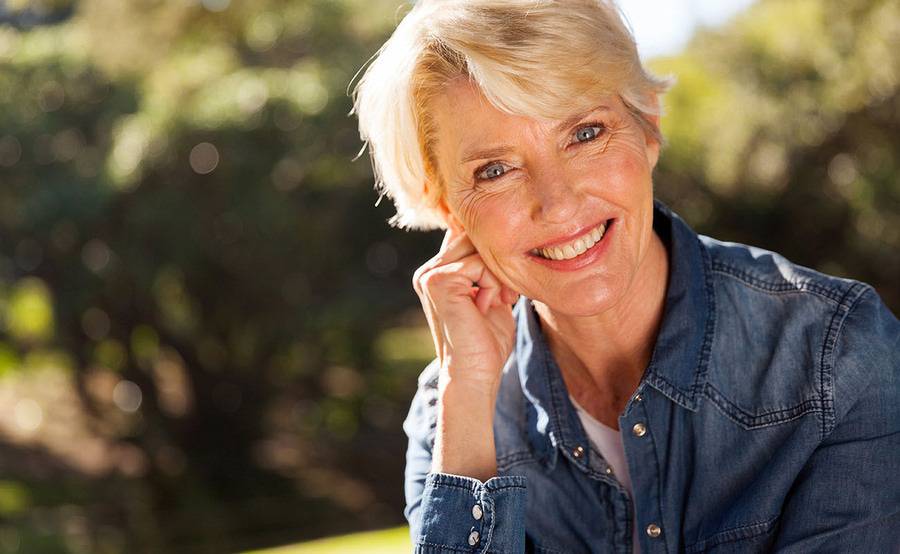 A smiling middle-aged woman represents a healthier life with treatment for venous disease or varicose veins.