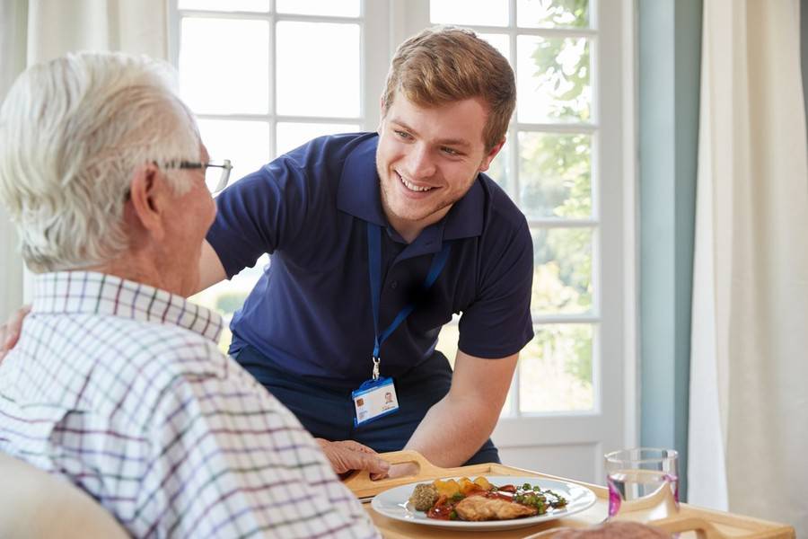 Patient in hospital bed  eating with volunteer.