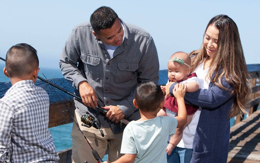 Vy Yamat stands with her third baby, husband and two young children at a pier having overcome cervical cancer with Scripps.