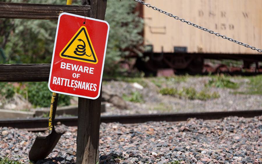 Red and yellow sign warning of rattlesnakes in area.