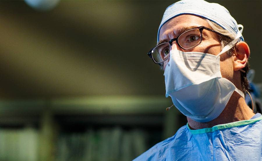 A heart surgeon with glasses and a mask who is preparing for a surgery.