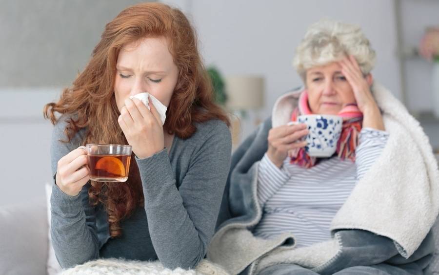 A mother and daughter fight cold and flu symptoms with hot tea and rest.