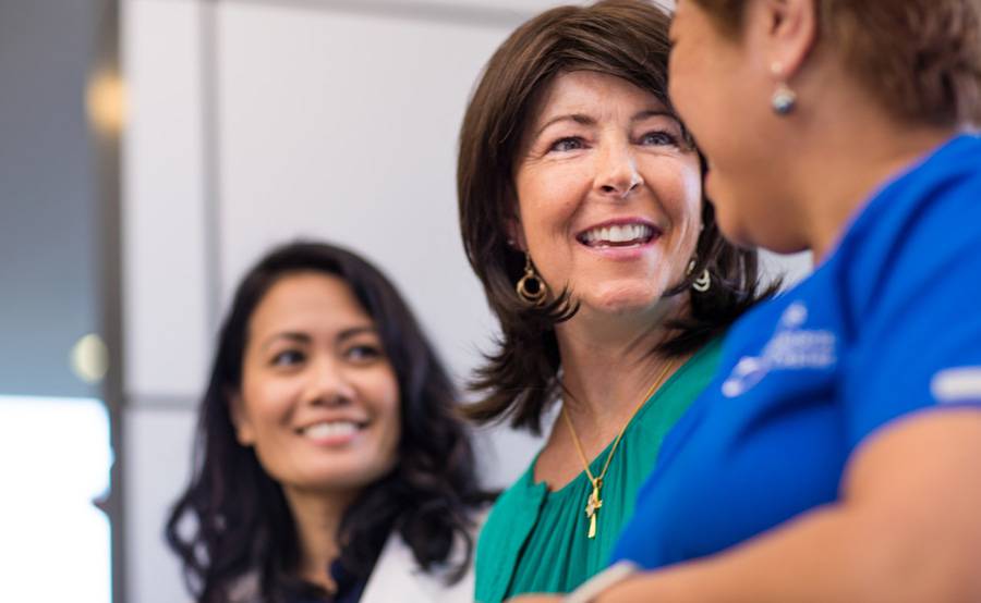 Three female Scripps employees smile and bond, representing life-long careers at Scripps.