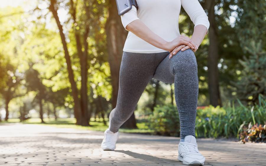 A woman stretching her legs outside in a park. 